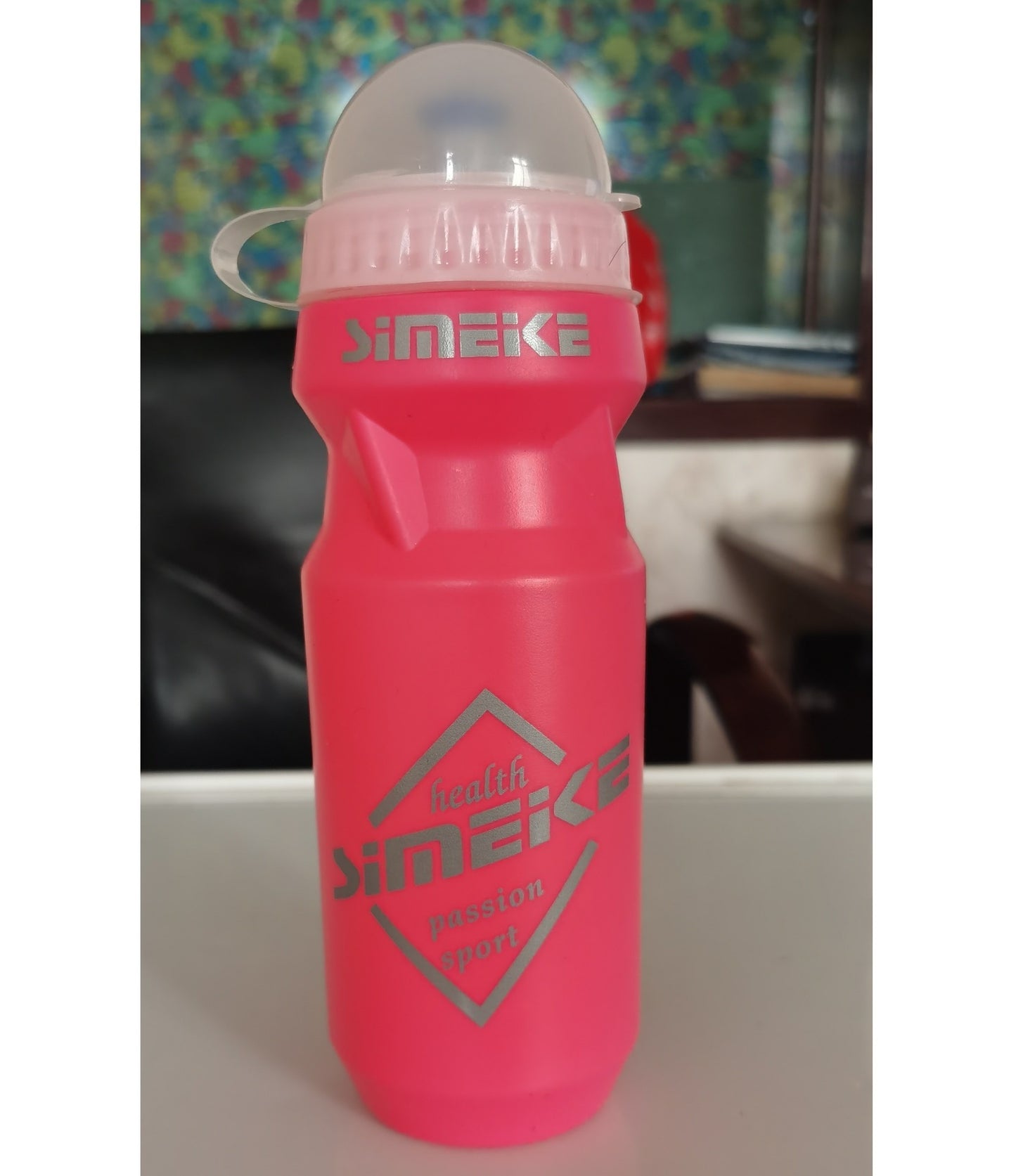 Pink water bottle with a transparent cap on a blurred background