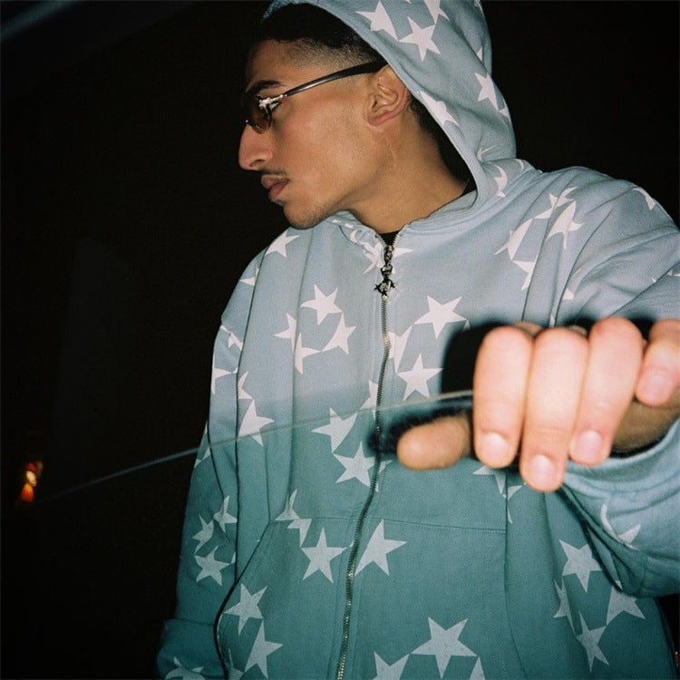 Person wearing a teal hoodie with star patterns, holding an object in a dark setting