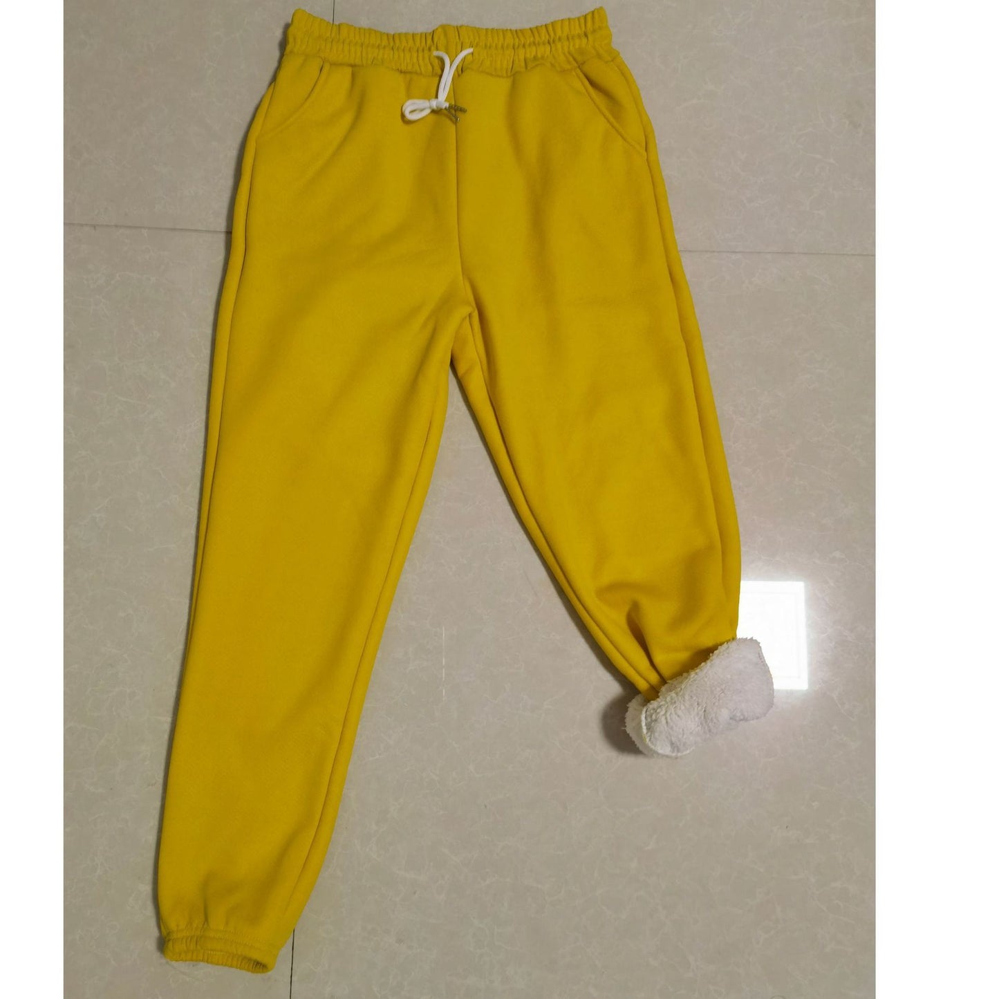 Yellow sweatpants on a light gray floor