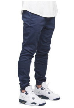 Person wearing navy jogger pants and white sneakers on a white background