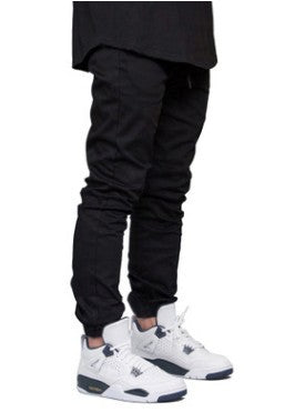 Person wearing black pants and white sneakers on a white background