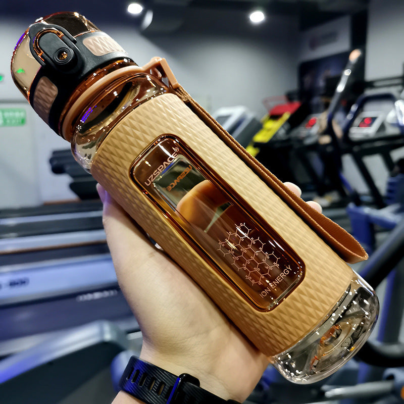 Wooden and metallic water bottle held in a hand with a blurred indoor background