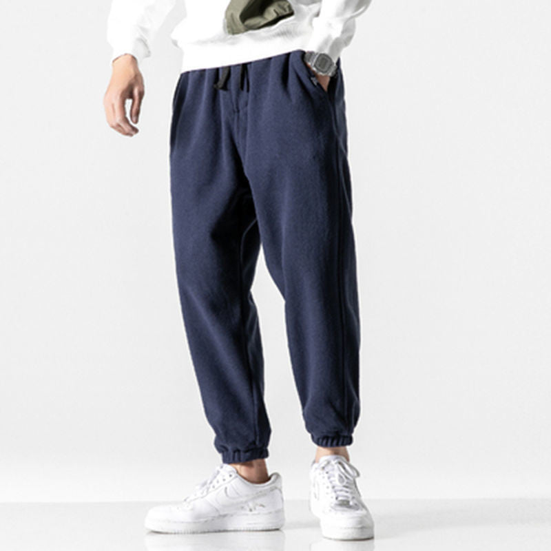 Person wearing navy jogger pants with a white background