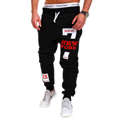 Black jogger pants with 'New York' text and patches on a white background