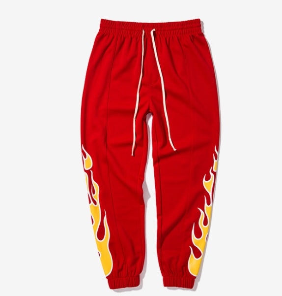 Red sweatpants with yellow flame designs on a white background