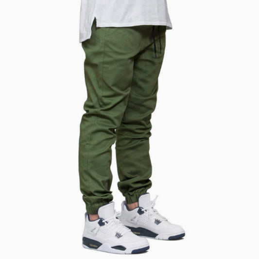 Green jogger pants worn with a white shirt and white sneakers on a white background