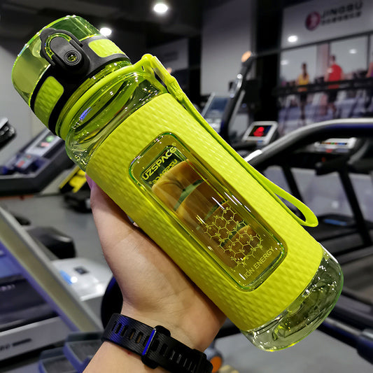 Yellow water bottle with a honeycomb design held in a hand, gym equipment in the background
