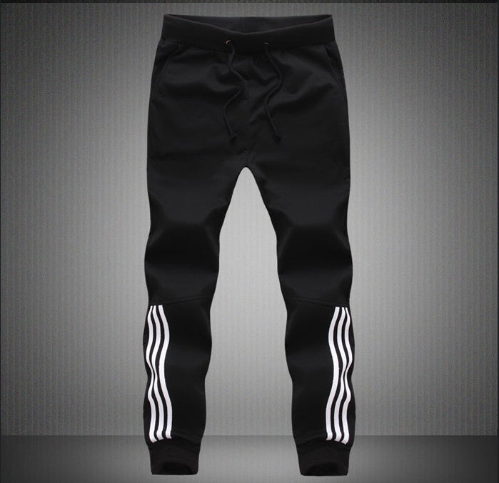 Black jogger pants with white stripes on a gray background