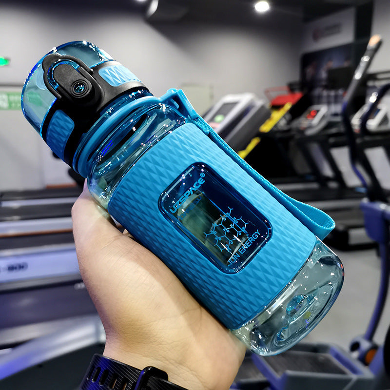 Blue water bottle with digital display held in a hand, gym equipment in the background