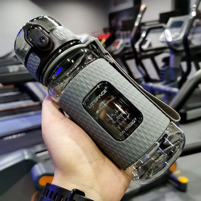 Person holding a futuristic water bottle with a blurred gym background