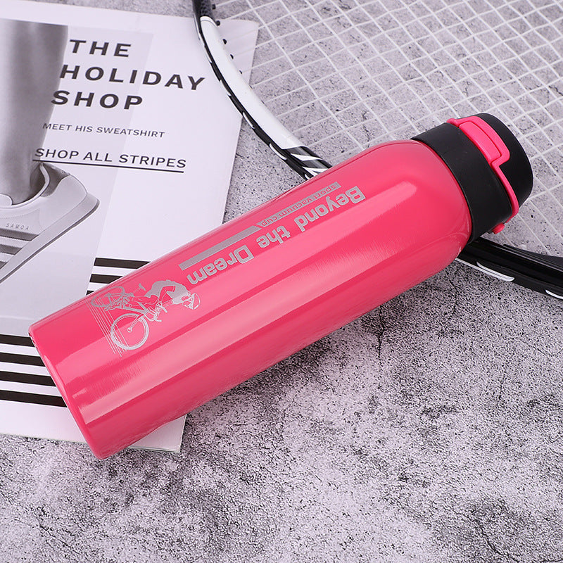 Pink water bottle with black lid on a textured surface with a magazine underneath