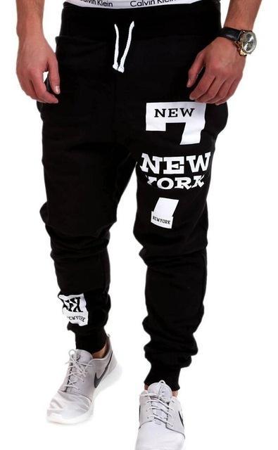 Black sweatpants with 'New York' text and white sneakers on a white background