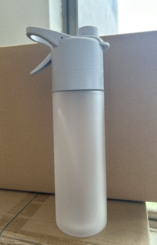 Clear spray bottle with white nozzle on a cardboard surface