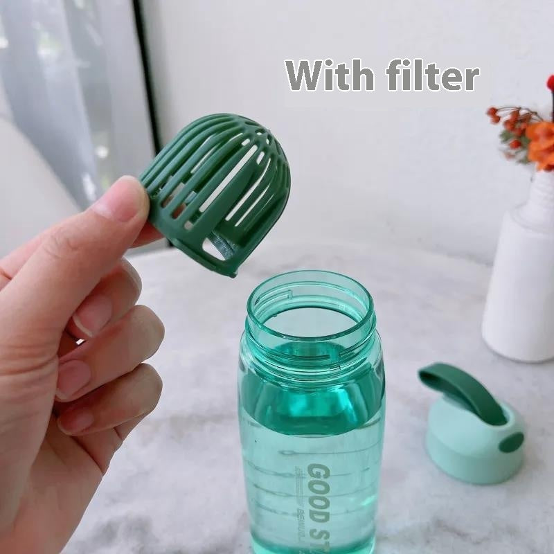 Green water bottle with filter attachment on a marble surface.