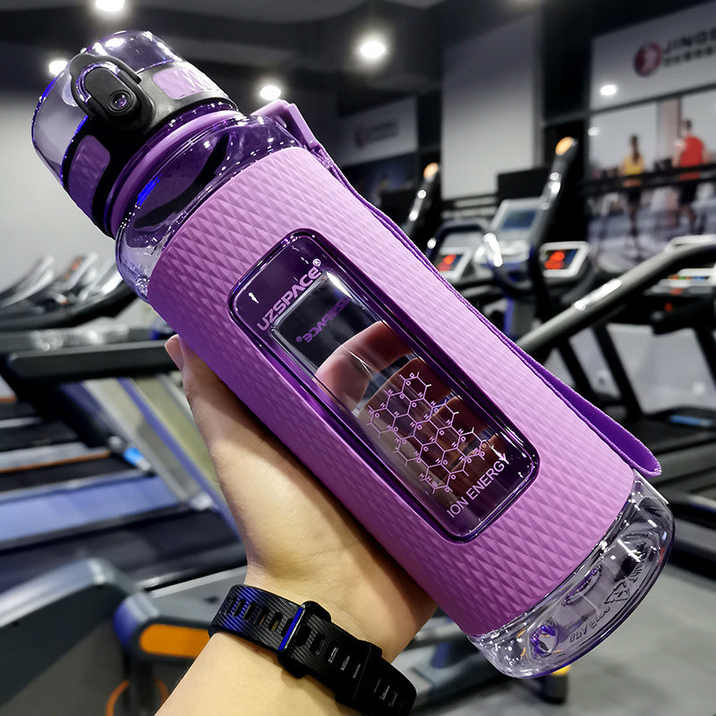 Purple water bottle with digital display held in a hand at a gym.