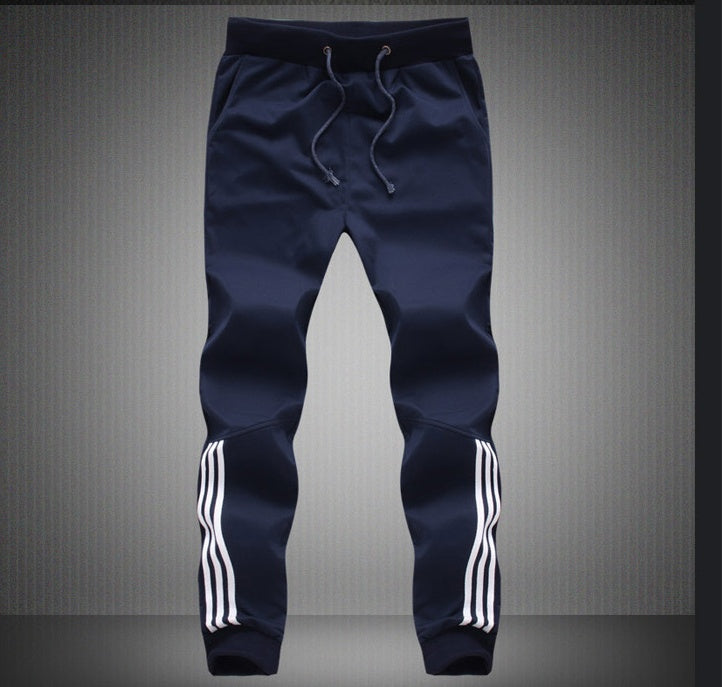 Navy blue jogger pants with white stripes on a gray background