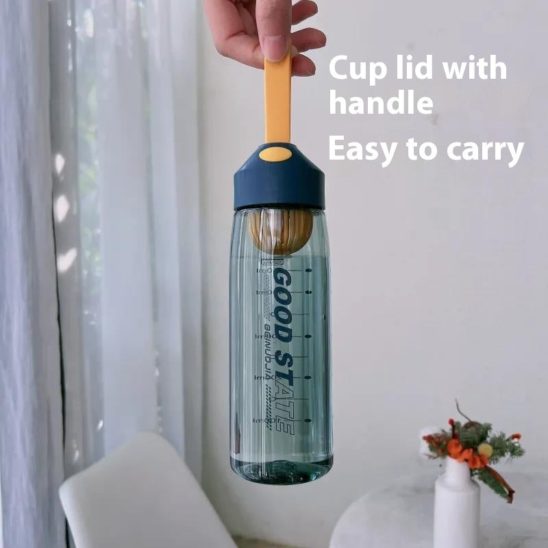 Clear water bottle with a blue lid and yellow handle, held by a hand against a light curtain background.