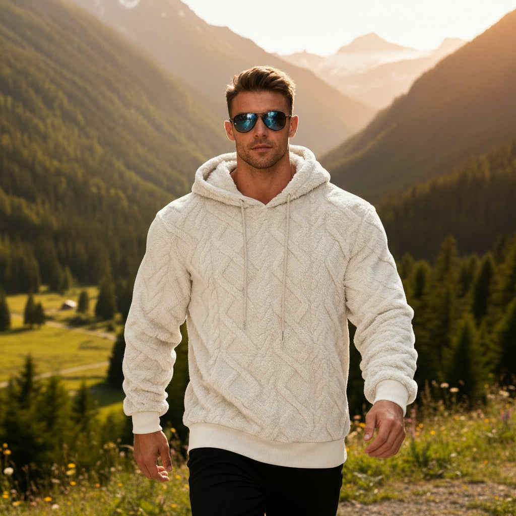 Man wearing a white cable knit hoodie and sunglasses on a city street.