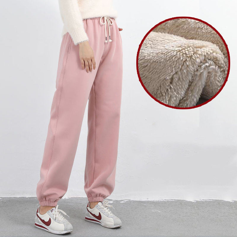 Pink sweatpants worn by a person with a close-up of the fabric texture on a white background.
