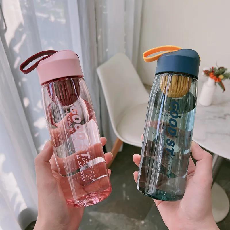 Two hands holding transparent water bottles with colorful lids.
