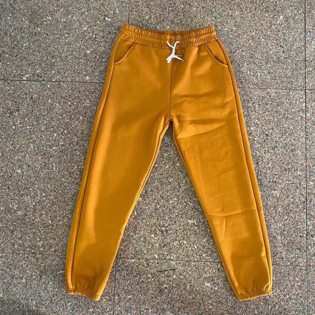 Mustard yellow sweatpants on a textured gray surface