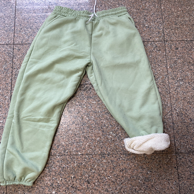 Green fleece pants with white cuffs on a brown tiled floor