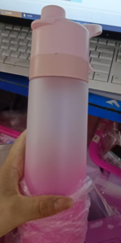 Pink water bottle held by a hand with a blurred background