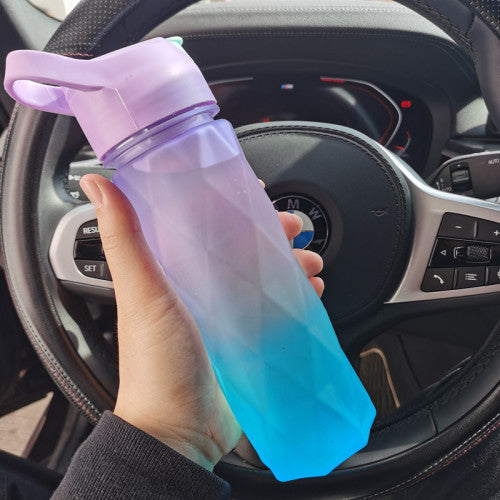 Gradient purple to blue water bottle held in a car interior